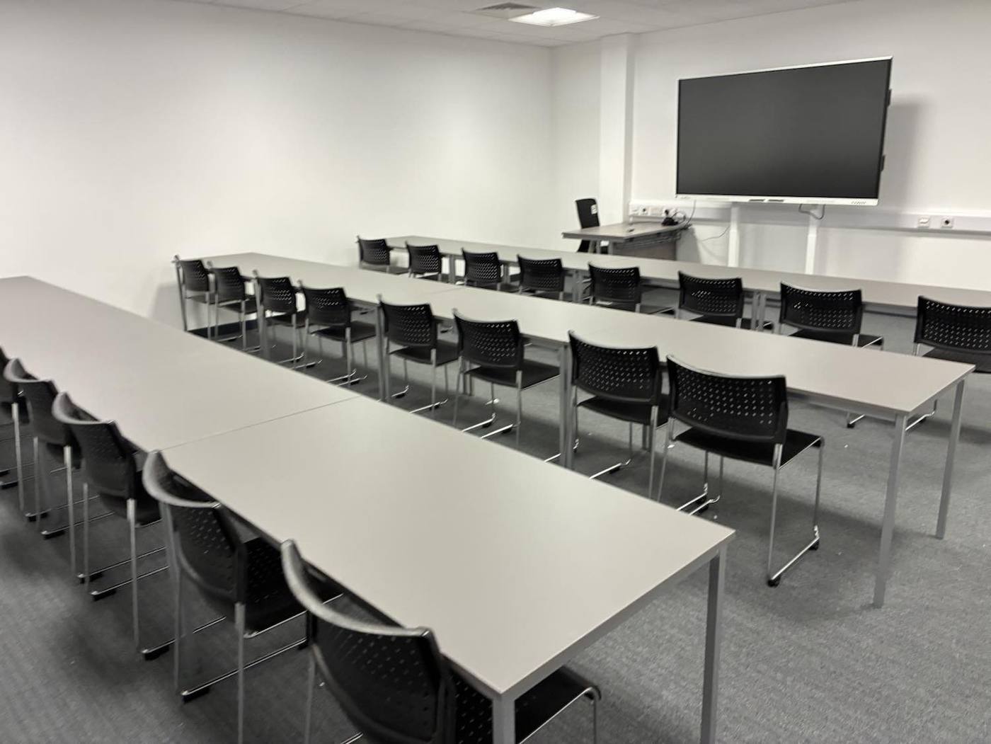 Teaching room with rows of tables and a wall screen